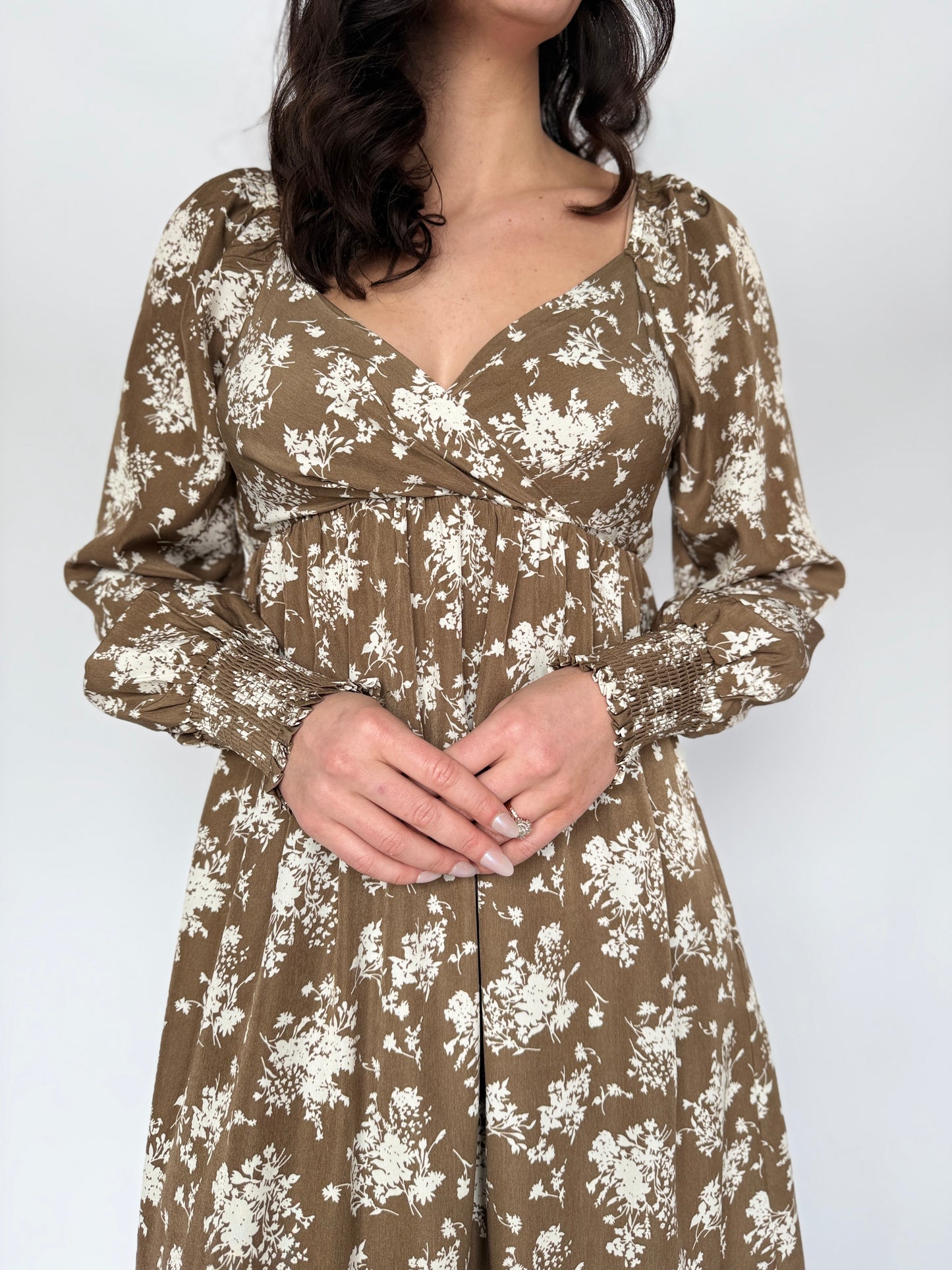 Woman wearing a floral dress with long sleeves on a white background