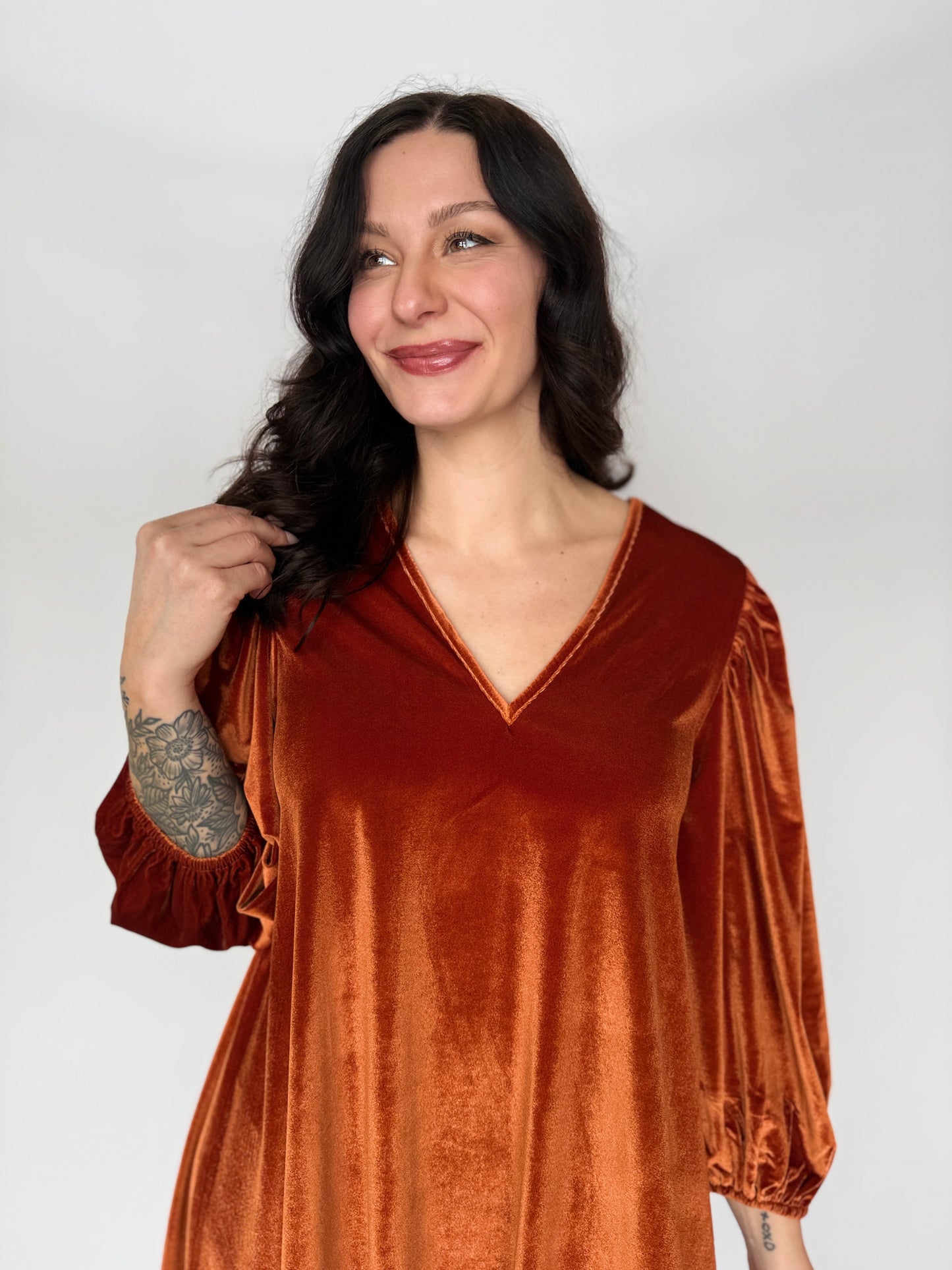 Woman wearing a rust-colored velvet dress against a white background