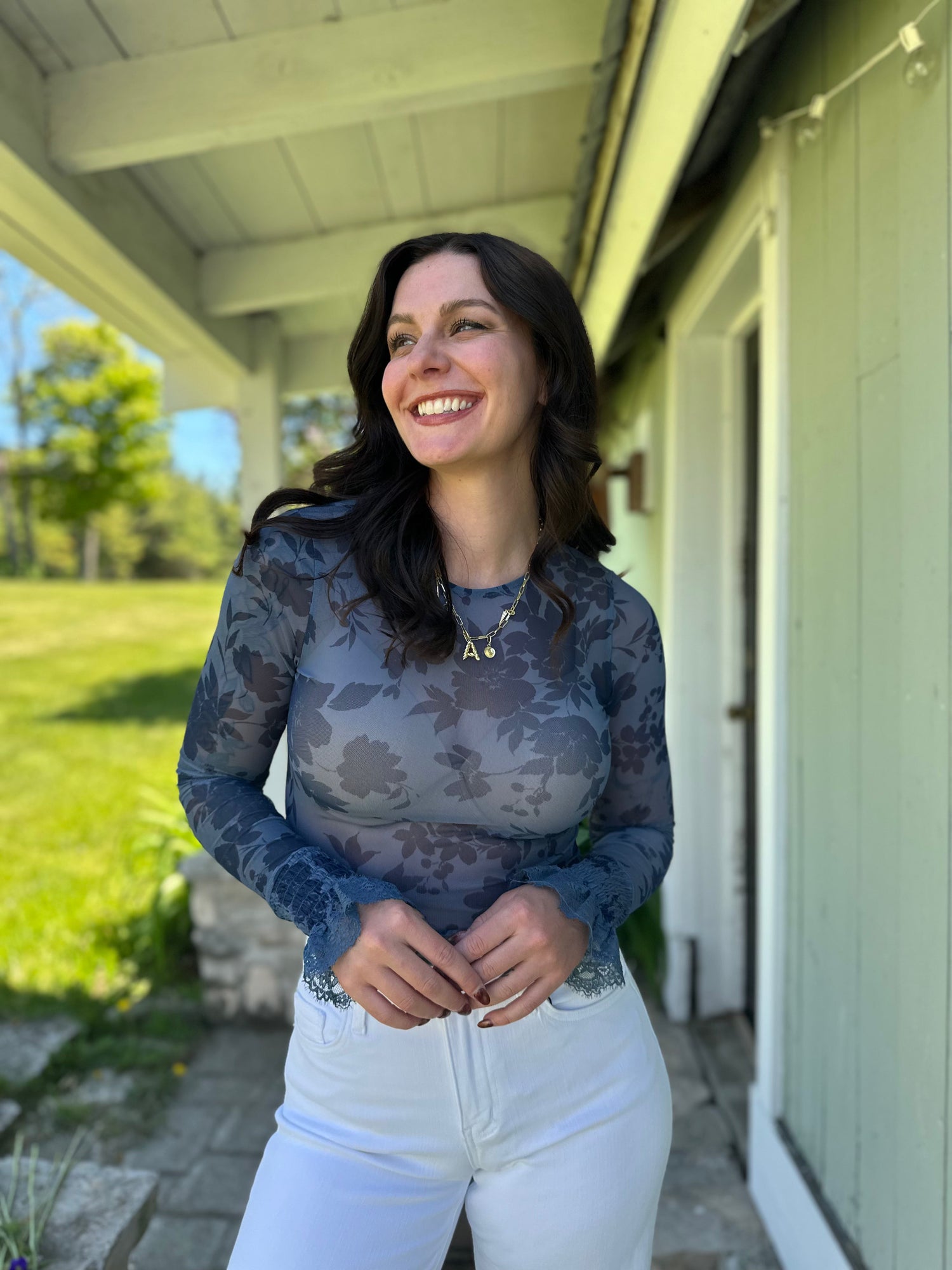 women wearing a pattern sweater and jeans outside on porch