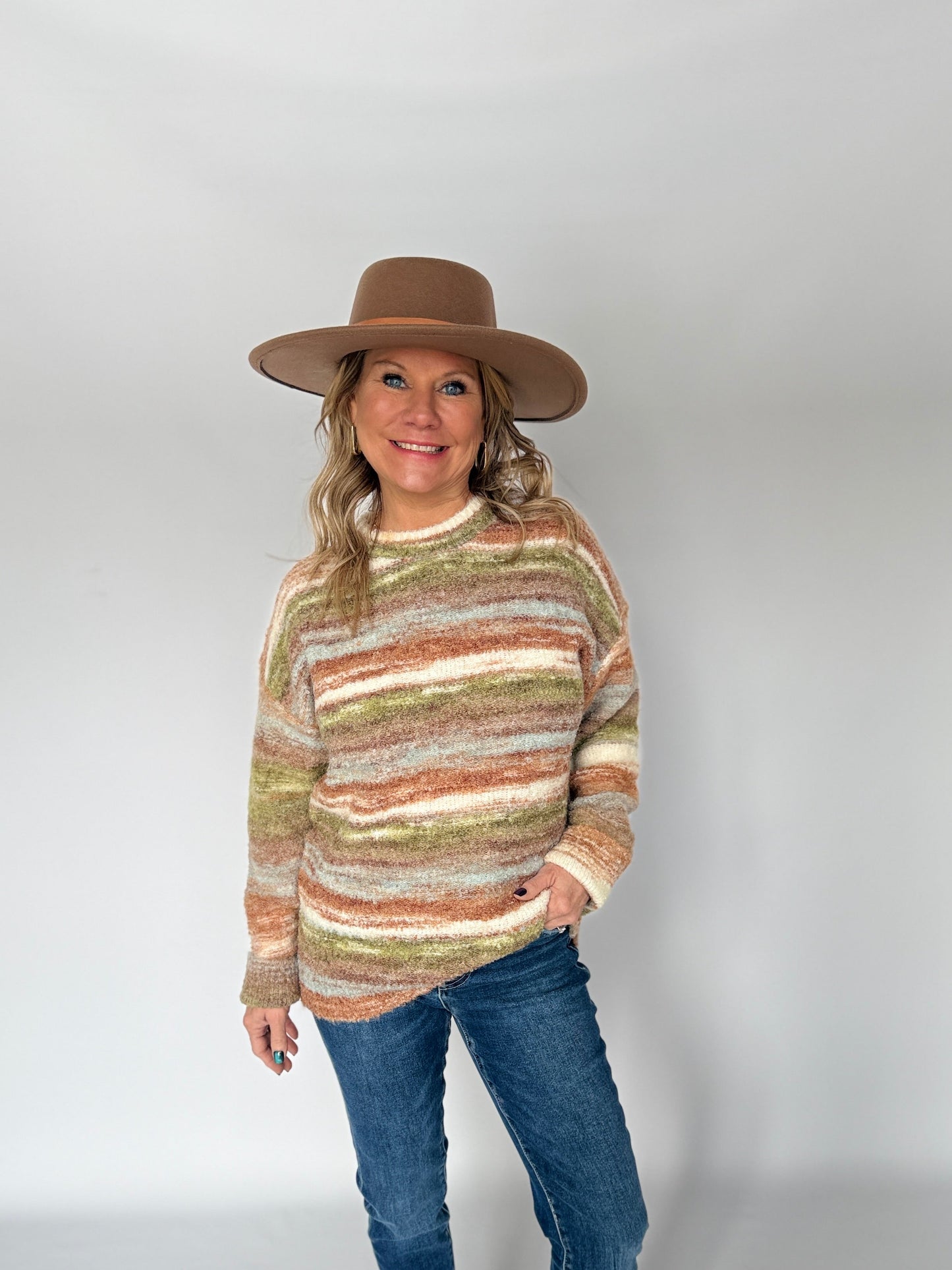 Person wearing a striped sweater, jeans, and a hat on a white background