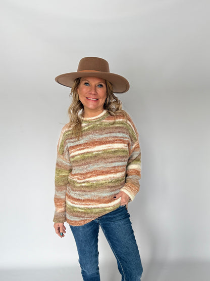 Person wearing a striped sweater, jeans, and a hat on a white background