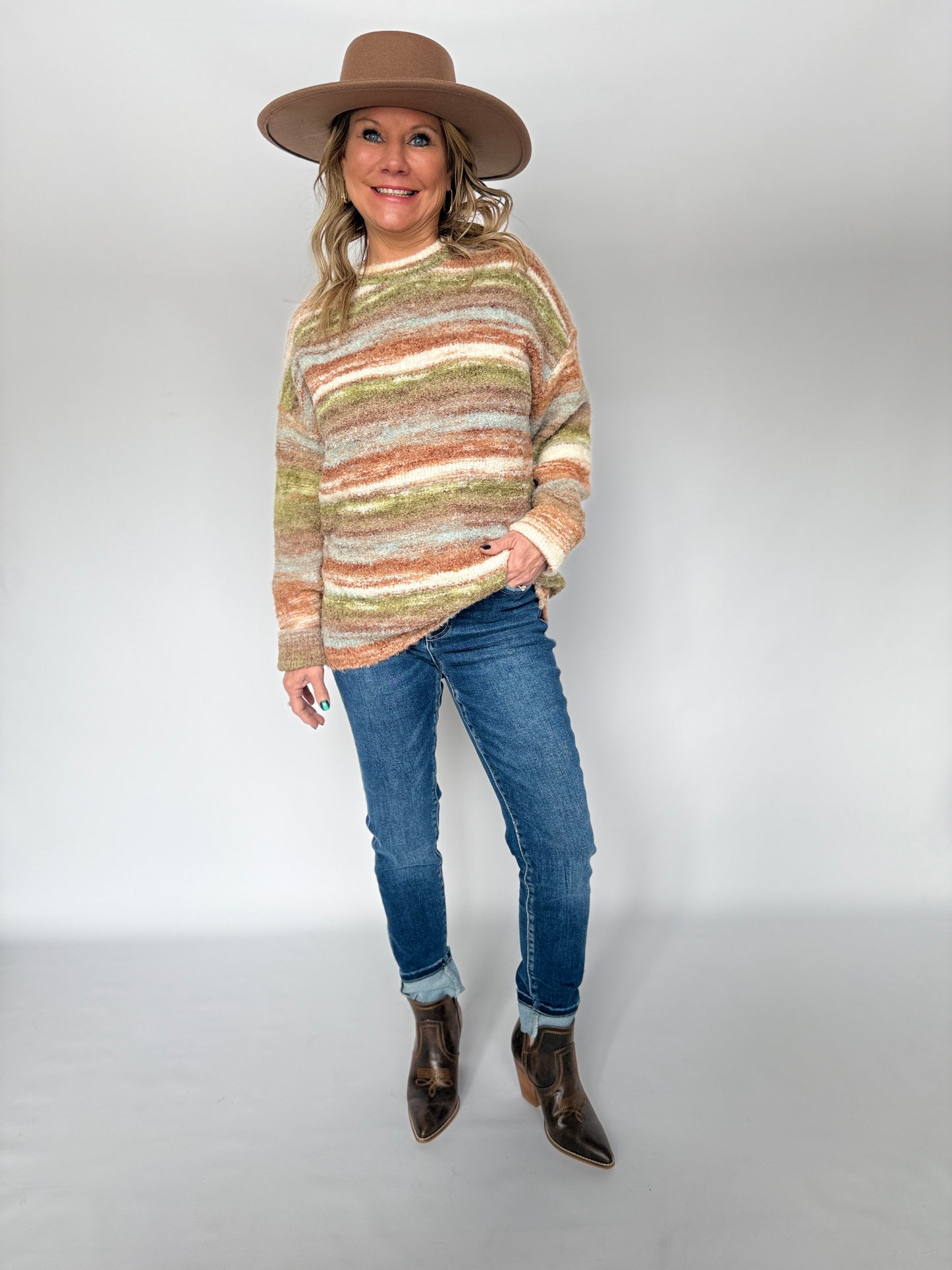 Woman wearing a striped sweater, jeans, and a hat on a white background