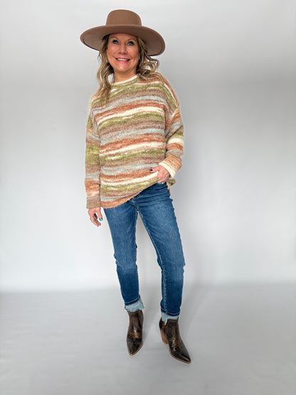 Woman wearing a striped sweater, jeans, and a hat on a white background