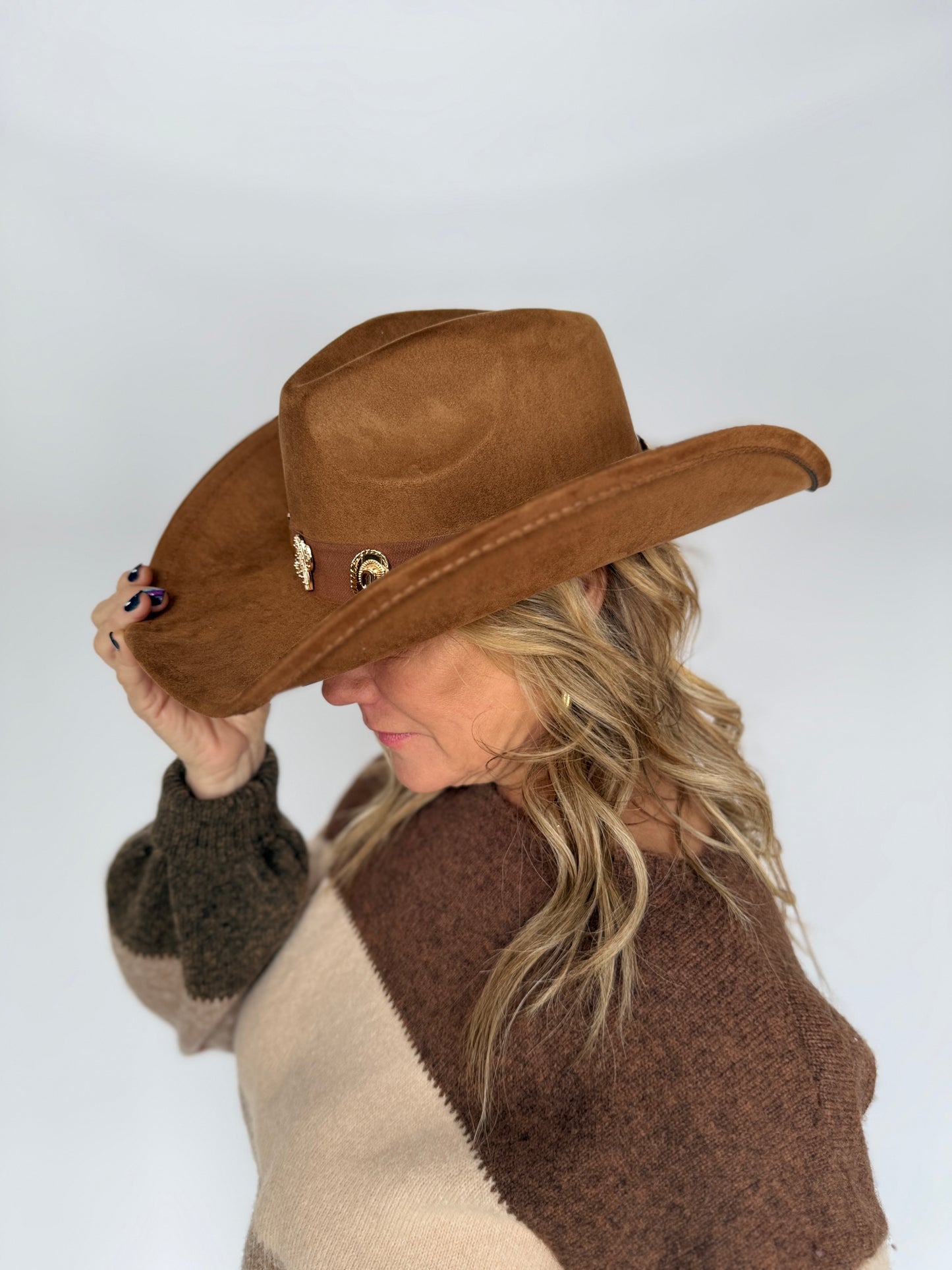 Person wearing a brown cowboy hat and patterned sweater against a white background