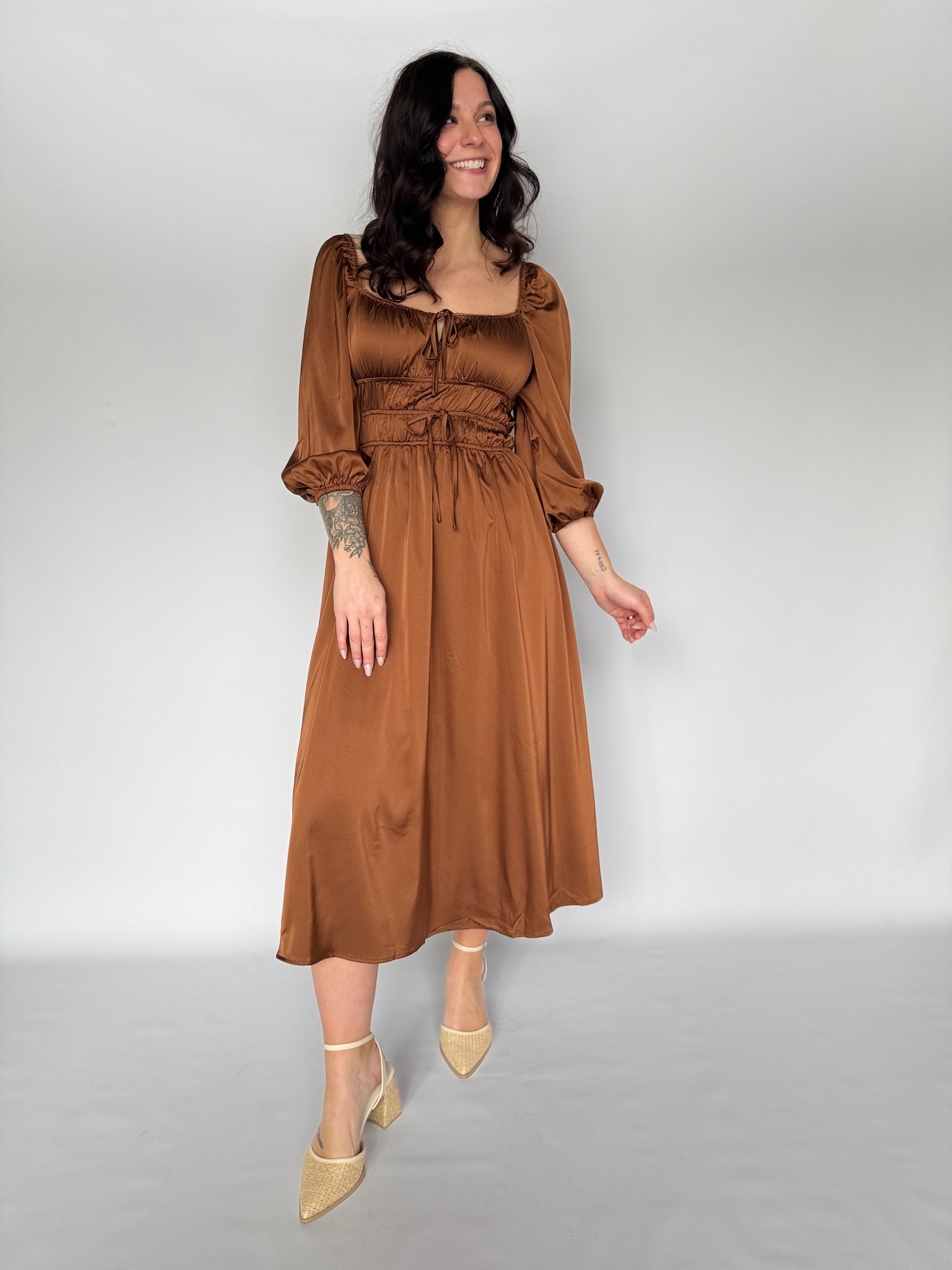 Woman wearing a brown dress against a plain background