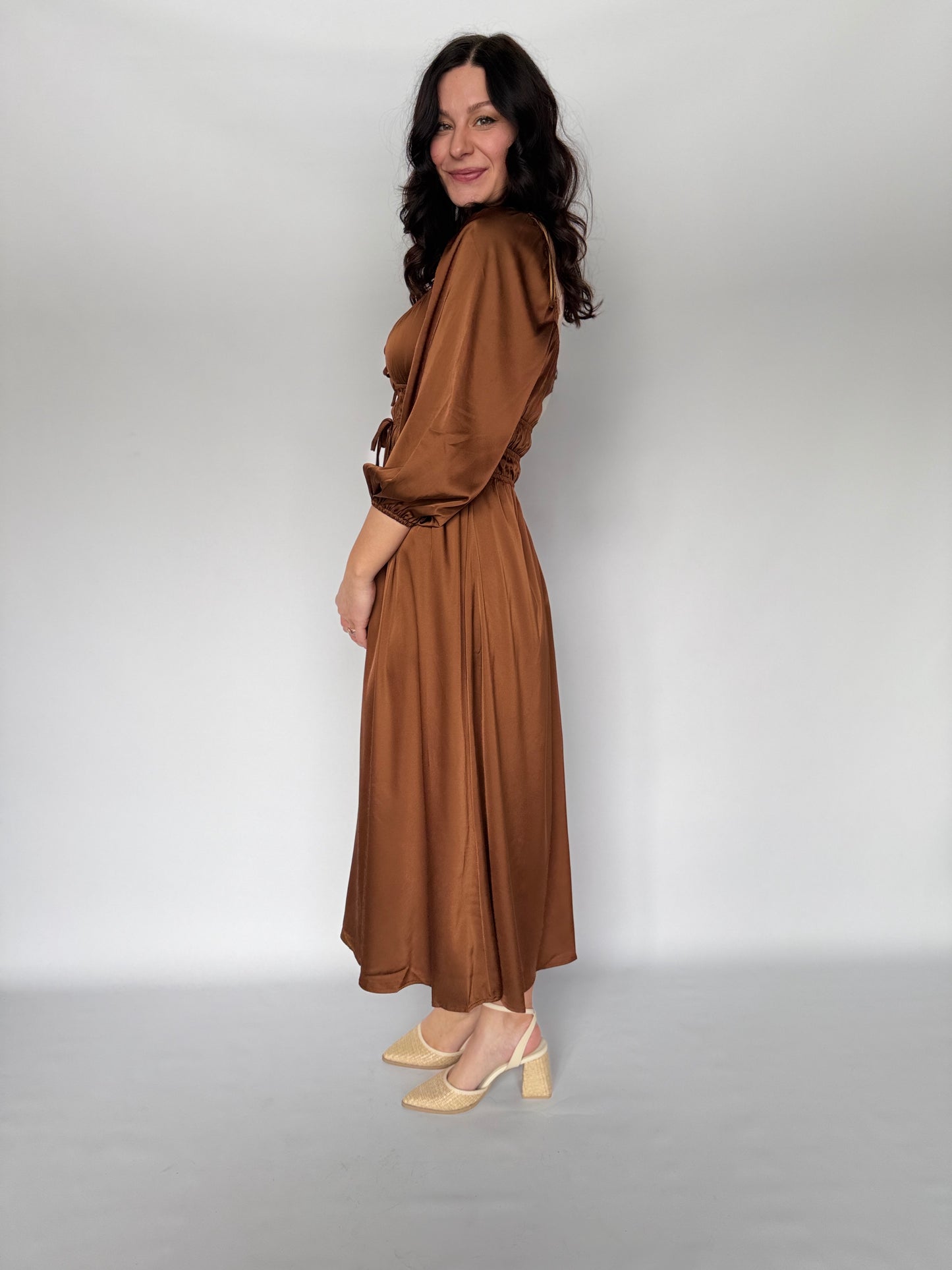 Woman wearing a brown dress against a plain background