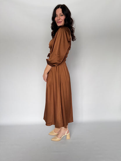 Woman wearing a brown dress against a plain background