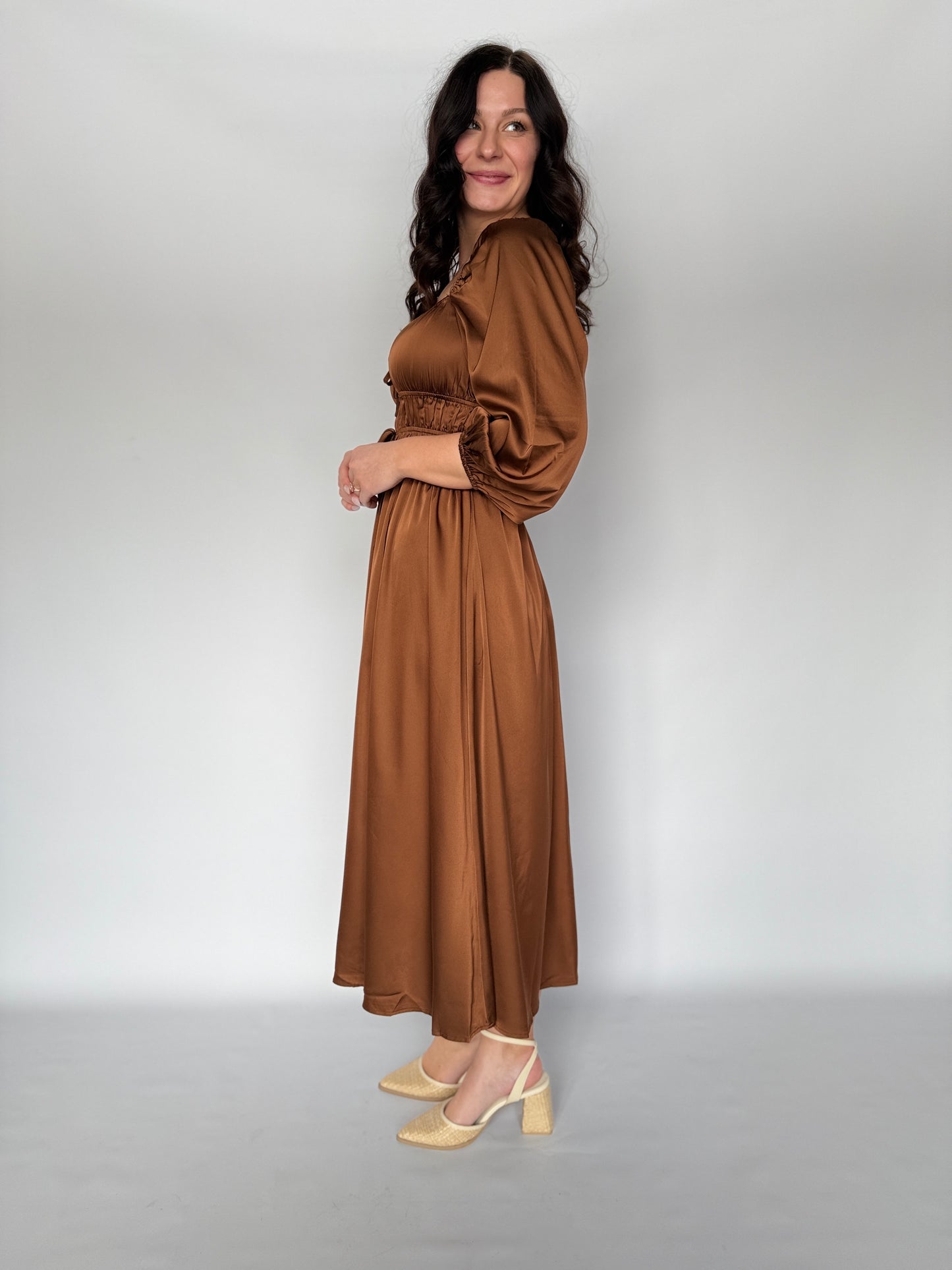 Woman wearing a brown dress against a plain background