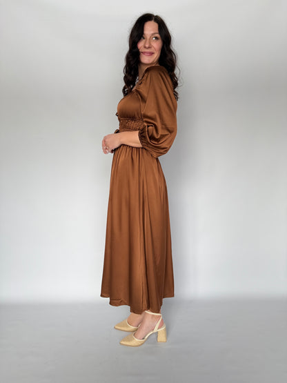 Woman wearing a brown dress against a plain background