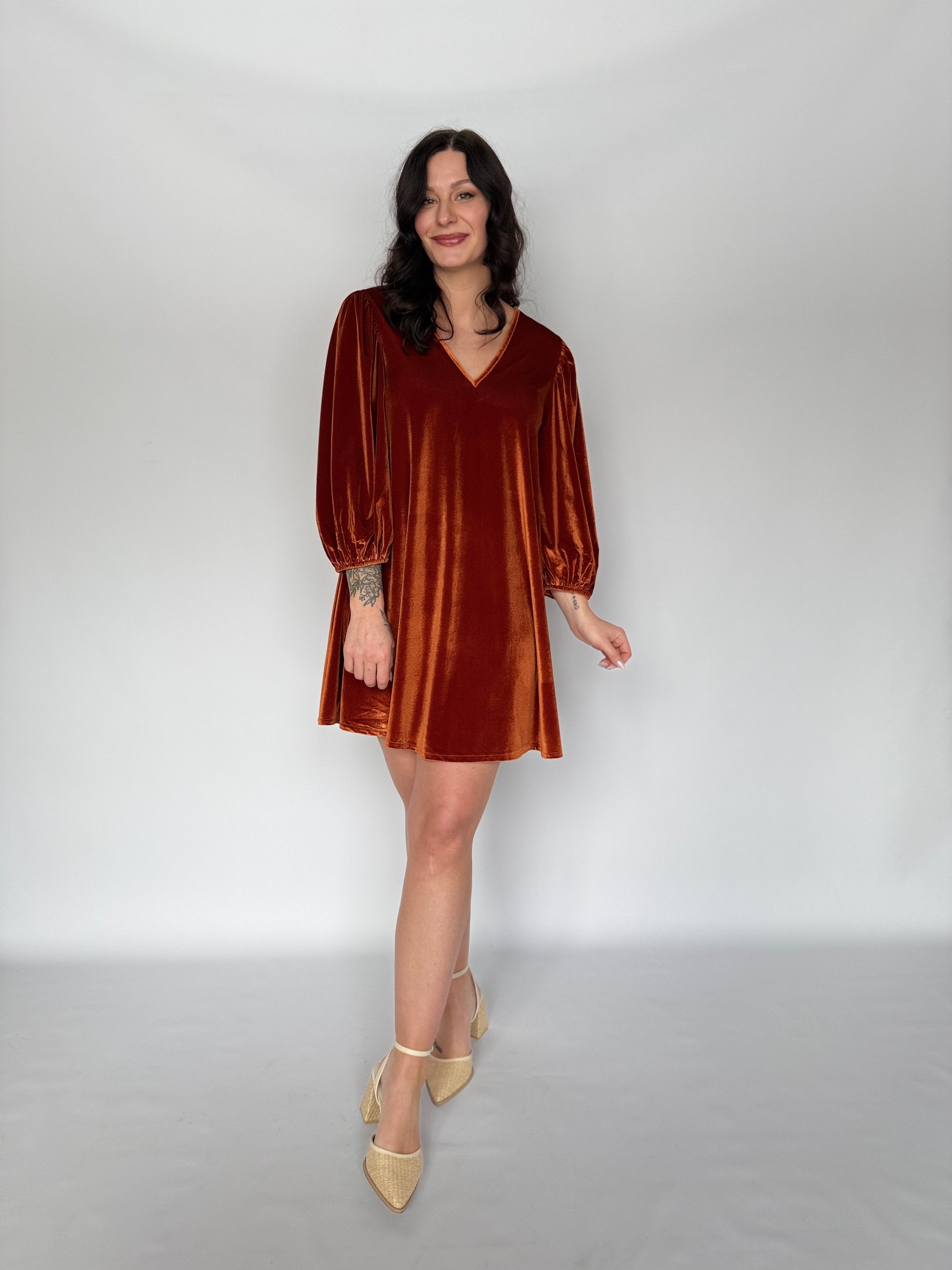 Woman wearing a brown velvet dress on a plain background