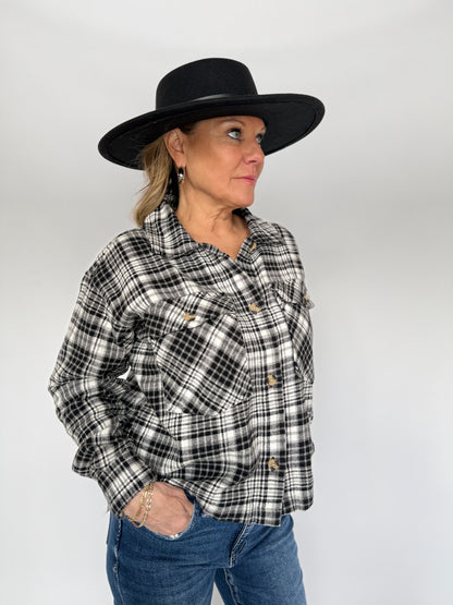 Person wearing a black and white plaid shirt, blue jeans, and a black hat on a white background