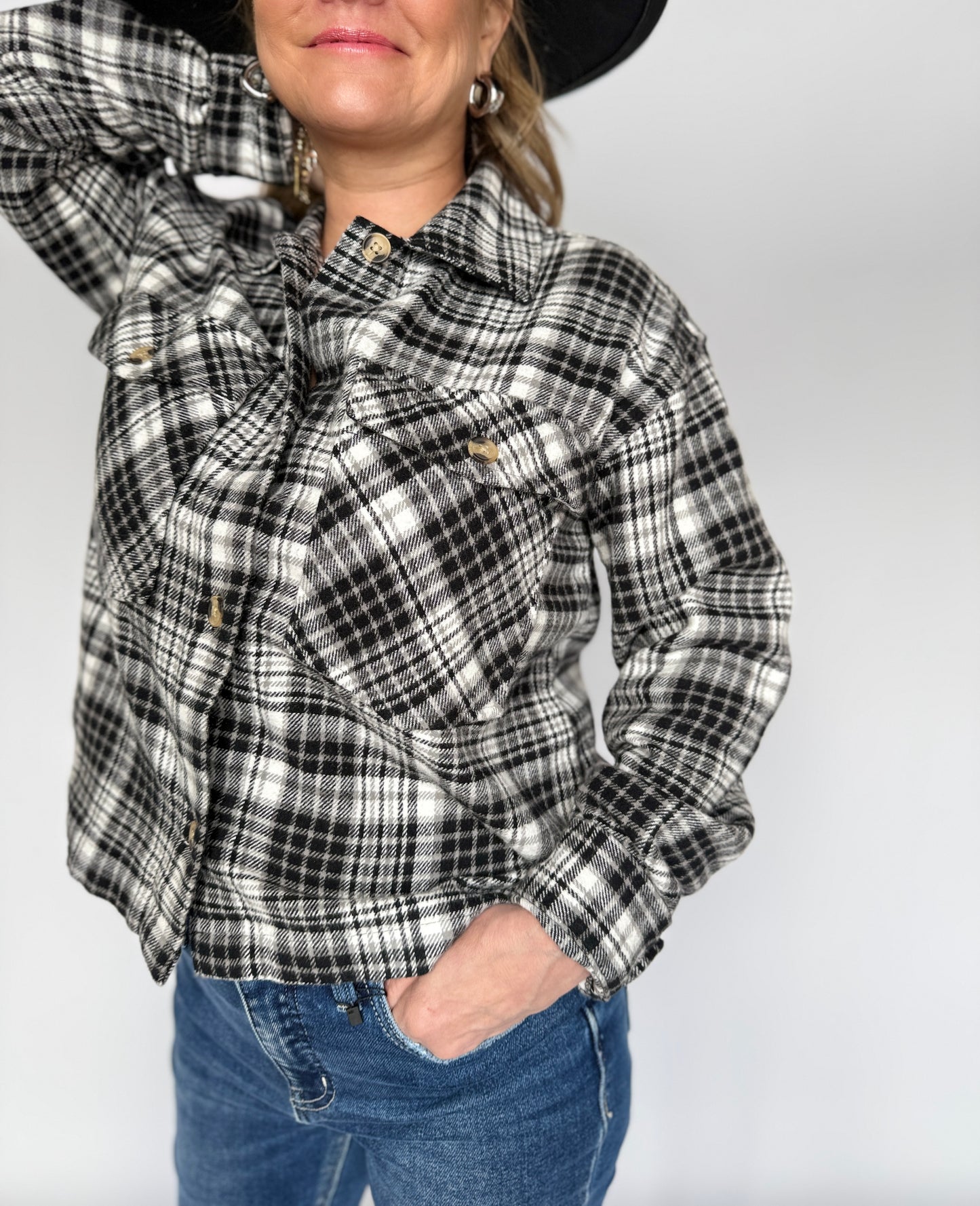 Person wearing a black and white plaid shirt with a plain background