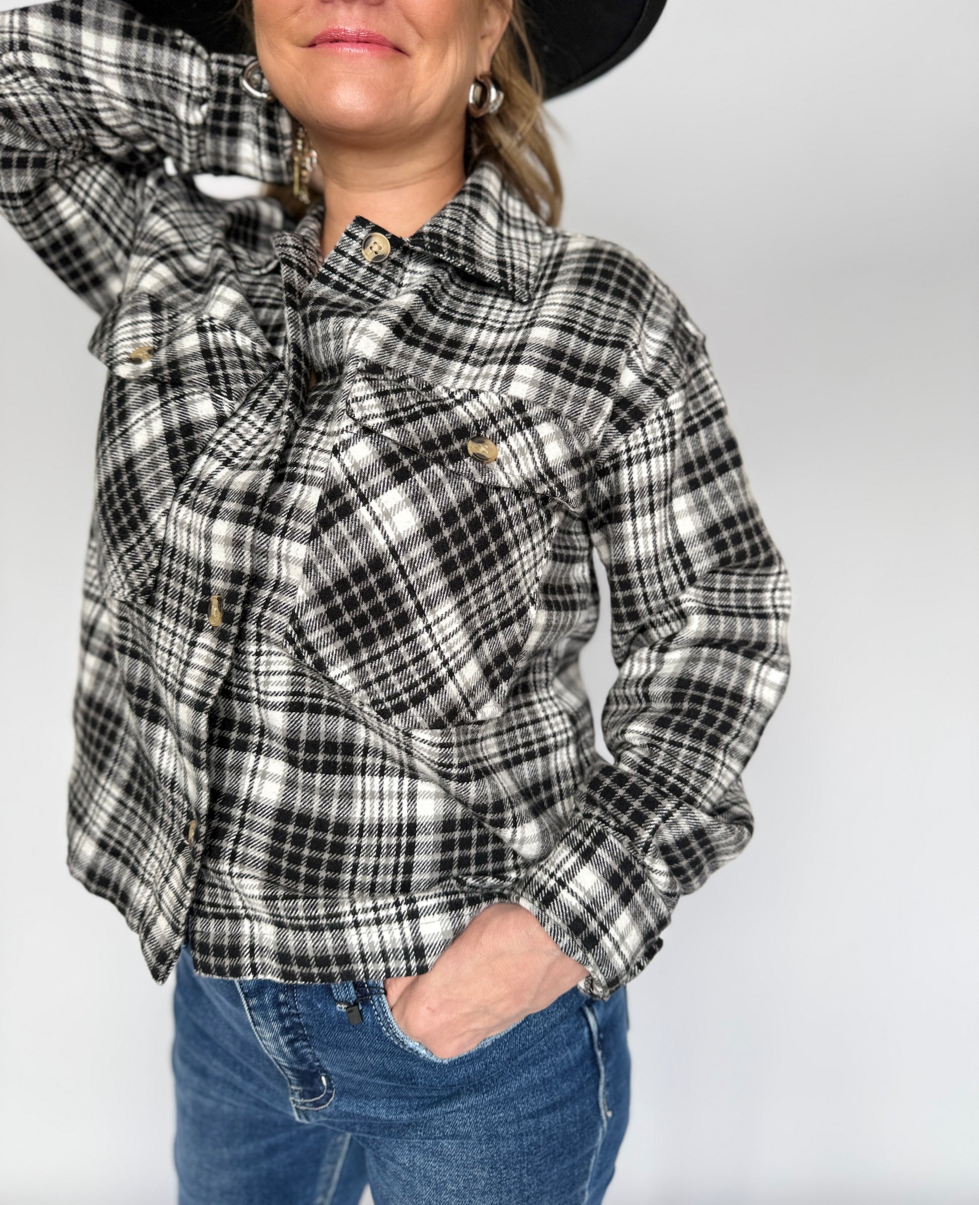 Person wearing a black and white plaid shirt with a plain background