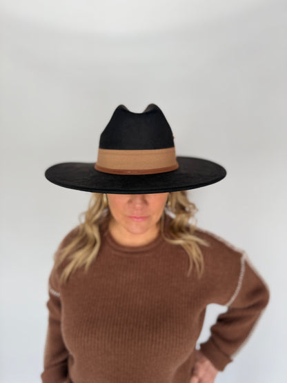 Person wearing a black and brown hat with a plain background