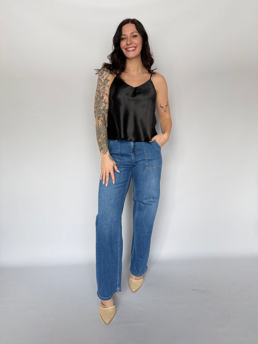 Woman wearing a black top and blue jeans against a white background