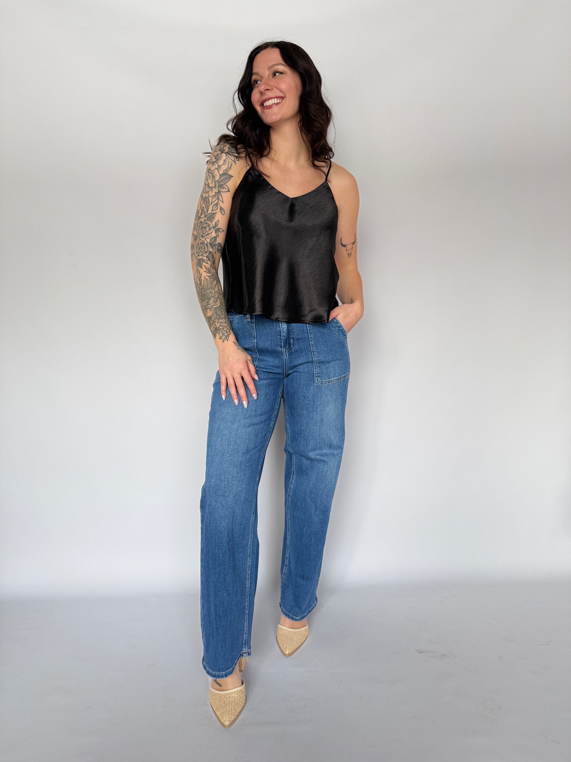 Woman wearing a black top and blue jeans against a white background