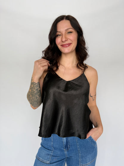 Woman wearing a black satin top and blue jeans against a white background